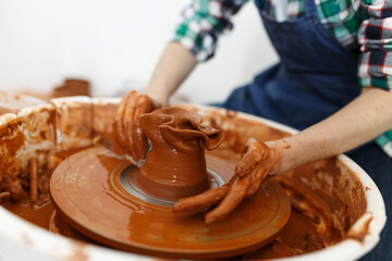 Unrecognisable female sculptor while she making clay pot on pottery wheel. Idea of small business and entrepreneurship. Home hobby, entertainment and leisure. Art studio