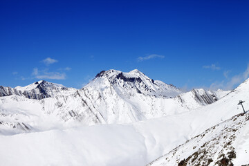 Off-piste slope and snowy mounts against blue sky