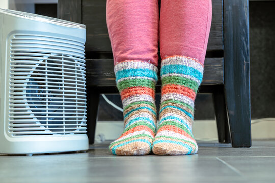Heating season. feet in socks. woman feet with socks. Room heating with electric heater at home. 