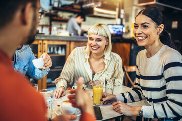 Young people have a great time in a cafe. Friends sitting in a coffee shop, drinking coffee, and having fun together.