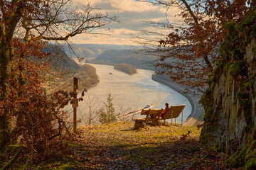 Mädchen sitz auf Bank und schaut sich den Rhein an im Spätsommer