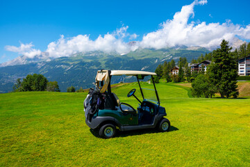 Crans Sur Sierre Golf Course with Hole 7 and Golf Cart with Mountain View in Crans Montana in Valais, Switzerland.