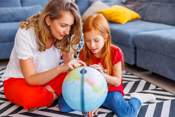 Mother and daughter learning geography using globe