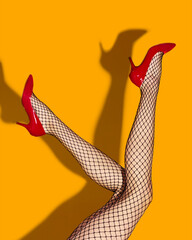Contemporary art collage. Female slim legs in fishnet socks and red heeled shoes on bright yellow background. Pop art photography. Vivid colors. Concept of creativity, imagination, artwork, lgbt, fun.
