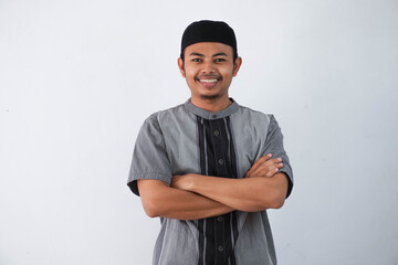 smile or happy young asian muslim man crossed arms and looking camera wearing grey koko clothes...