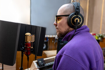 Male musician singing into a professional microphone. Voice recording in studio. Music production