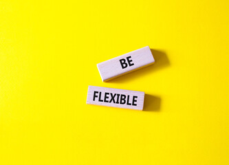 Be Flexible symbol. Wooden blocks with words Be Flexible. Businessman hand. Beautiful yellow background. Business and Be Flexible concept. Copy space.