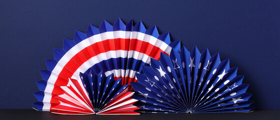 American flag paper fans on dark blue background. USA patriotic and Fourth of July party decorations.