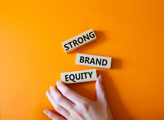 Strong Brand Equity symbol. Concept words Strong Brand Equity on wooden blocks. Businessman hand. Beautiful orange background. Business and Strong Brand Equity concept. Copy space