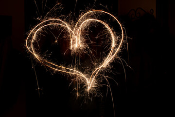 Different figures, letters or drawings created at night with flares; infinity symbol, a heart, cross or different letters
