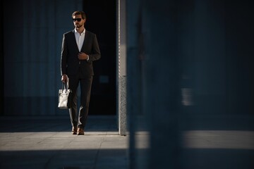 Elegant handsome man in classic suit standing near the office building.