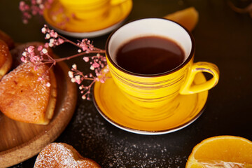 Yellow cups, tea time and homemade heart shaped muffins. Cupcakes with orange flavour for Valentines Day breakfast.