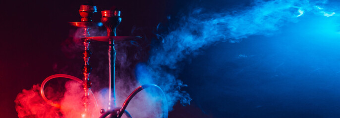 Modern hookah, shisha on a smoky black background with neon lighting and smoke. Place for your...