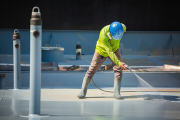 A male worker holding an industrial spray gun used for roof plate tank surface on steel industrial...