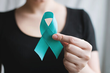 Woman holds in his hand Teal ribbon. Symbolic for cervical cancer, ovarian cancer, gynecological cancer and PCOS. And sexual assault awareness. Women's health care
