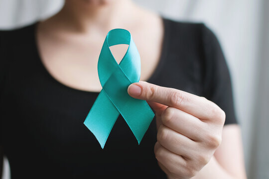 Woman Holds In His Hand Teal Ribbon. Symbolic For Cervical Cancer, Ovarian Cancer, Gynecological Cancer And PCOS. And Sexual Assault Awareness. Women's Health Care