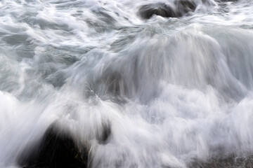 olas de aspecto blanco y sedoso rompiendo en una roca en el mar emitido espuma al viento