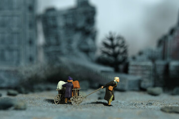 Miniature people toy figure photography. An elder couple with a grandchild refugee walking, moving...