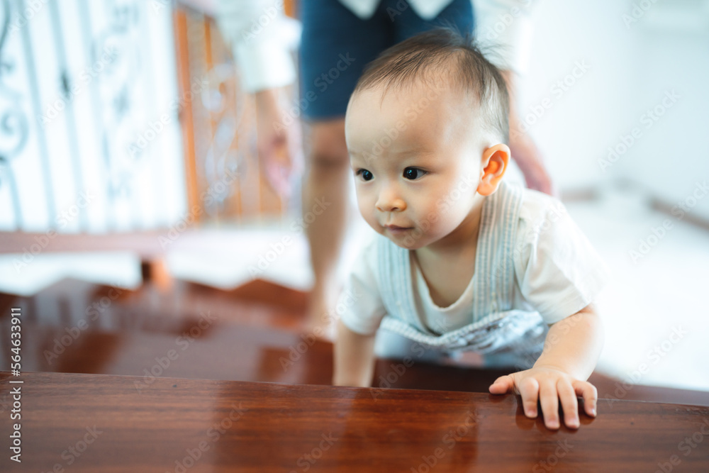 Wall mural Chubby ginger baby boy in bodysuit, barefoot. He smiling, creeping on floor background with copy space, family fatherhood and parenthood concept, happy little baby girl with father at home