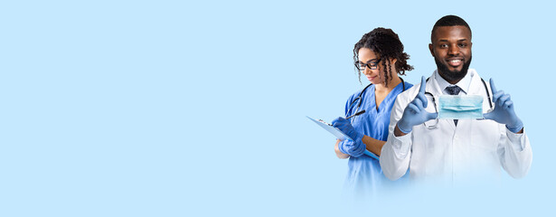 Cheerful african american doctor and nurse working on blue background