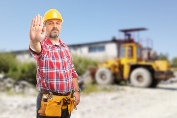 Bossy man showing stop gesture in front of machinery