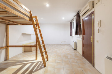 a studio apartment with a raised bed in a pine wood structure with a staircase, electric heaters and a glossy sapele armored door