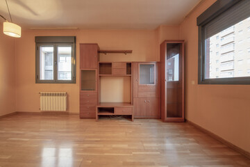Corner of a room with no more furniture than a bookcase with drawers and cabinets on one side of the wall