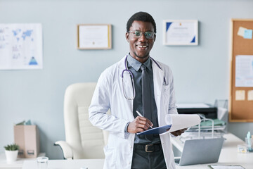 Young African American doctor holding clipboard smiling at camera