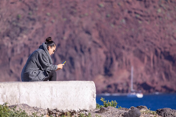 Mujer usando móvil junto al mar