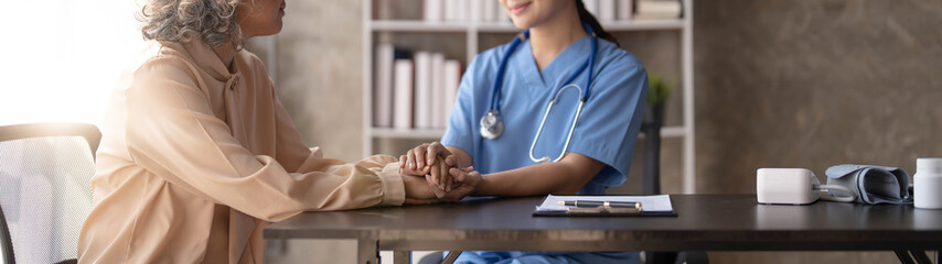 Happy patient is holding caregiver for a hand while spending time together. Elderly woman in...