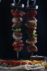 Shish kebab with grilled vegetables served with french fries and garlic sauce on a wooden table