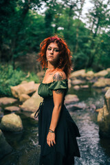 Chica guapa pelirroja con vestido antiguo en un bosque verde frondoso y misterioso