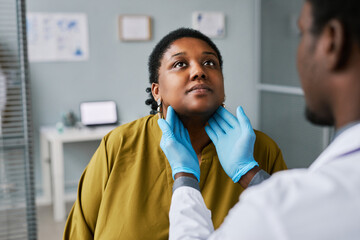 Black woman at health checkup with doctor palpating neck