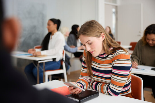 Young woman using cell phone at workshop