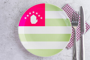 A Plate with the Flag of Abkhazia, Cutlery and Napkins on the Mable Table.