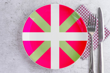 A Plate with the Flag of Basque Country, Cutlery and Napkins on the Mable Table.