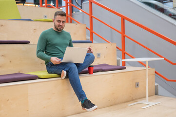 Caucasian man working on laptop in coworking space. Open space.
