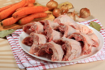 Fresh chicken skeletons and vegetables, carrots and onions. Raw chicken backs skin on bone