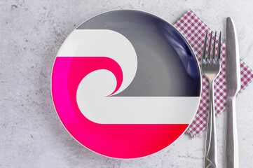 A Plate with the Flag of Maori, Cutlery and Napkins on the Mable Table.