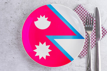 A Plate with the Flag of Nepal, Cutlery and Napkins on the Mable Table.