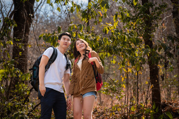 Young Asian couples have fun together in park, tourist outdoor adventure trip lifestyle spend time together trekking in forest during vacation or holiday, Adorable girl have happy time with boyfriend