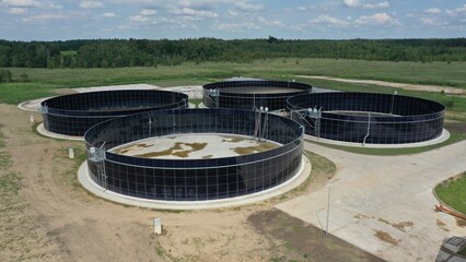 Large round metal tanks for storing liquid waste from an agricultural farm. Open-top open-air tanks for cow manure processing at an agricultural farm. Evaporation of manure.