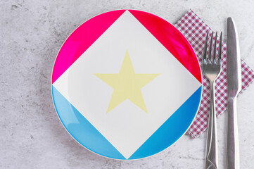 A Plate with the Flag of Saba, Cutlery and Napkins on the Mable Table.