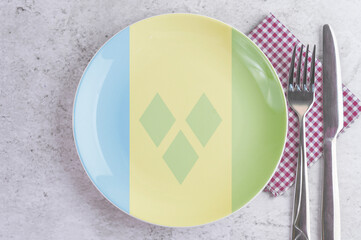 A Plate with the Flag of Saint Vincent and the Grenadines, Cutlery and Napkins on the Mable Table.