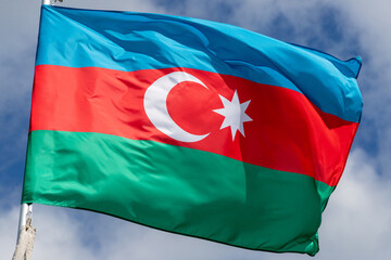 the national flag of azerbaijan flutters in the wind in the blue sky