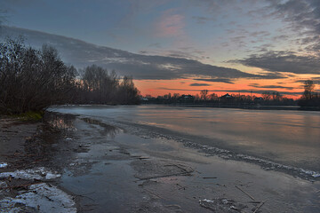 River with thin ice at the setting sun