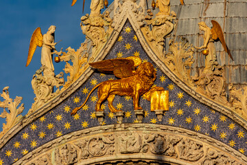 Winged lion sculpture (symbol of Venice) on St. Mark's basilica facade in center of Venice, Italy (translation "Peace to you, Mark, my Evangelist")