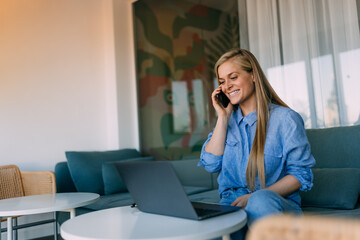 Businesswoman making a phone call while working over the laptop.