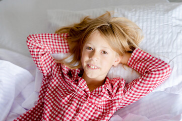 Image of young smiling pretty girl lies in bed indoors.