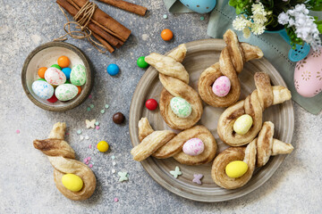 Easter bake idea. Easter rabbit-shaped buns puff pastry with  cinnamon on a stone tabletop. View from above.